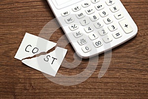 Cut the word cost concept for recession or credit crisis and calculator on wood. Concept of cost cut.