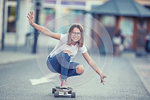 Cut young skater girl riding on her longboard in the city