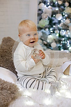 Cute 1 year old baby boy in cozy clothes, posing in New Year dec