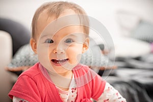 Cute 1 year old baby girl laughs into camera big brown eyes and wide smile with new teethes, concept of teething