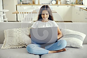 Cute 12s girl use laptop sit on sofa in living room