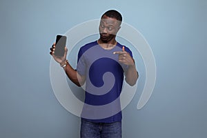 cute 25s african guy in casual blue t-shirt showing ads on smartphone screen