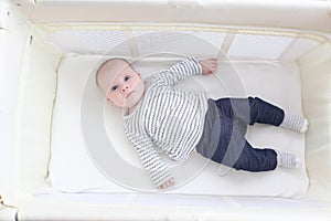 Cute 3 months girl lying in travel crib