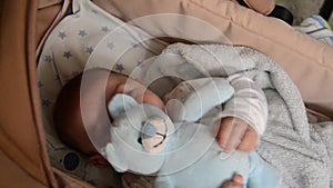 Cute 3 months old baby boy making funny faces in baby carry cot