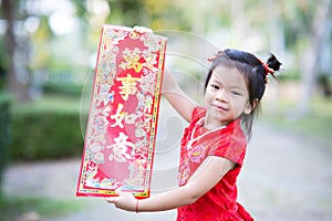 Cute 4 year old Asian kid girl holding red greeting placard with golden Chinese characters meaning Fulfillment.