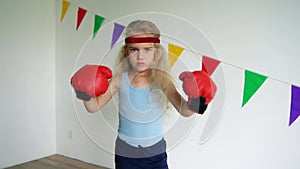 Cute 4 years old girl with boxing gloves. Child training self-defense