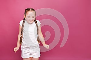 Cute 7-8 years old girl frowns with closed eyes on pink background