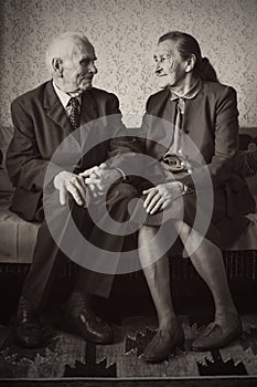 Cute 80 plus year old married couple posing for a portrait in their house. Love forever concept