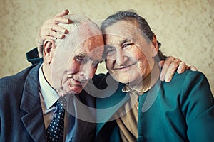 Cute 80 plus year old married couple posing for a portrait in their house. Love forever concept