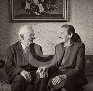 Cute 80 plus year old married couple posing for a portrait in their house. Love forever concept.