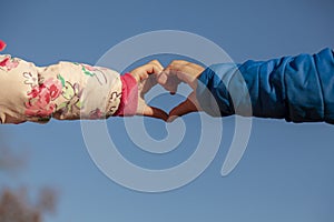 A cute abstract image showing the touching hands of a girl with pink coat and a boy with blue coat.