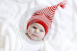 Cute adorable baby child with Christmas winter cap on white background. Happy baby girl or boy smiling and looking at