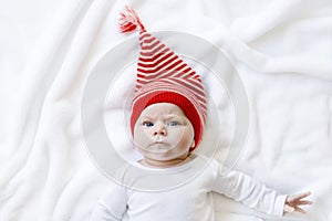 Cute adorable baby child with Christmas winter cap on white background. Happy baby girl or boy smiling and looking at