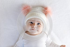 Cute adorable baby child with warm white and pink hat with cute bobbles