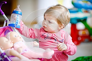 Cute adorable baby girl holding nursing bottle and drinking formula milk or water. First food for babies. Healthy babies