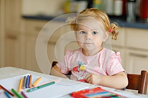 Cute adorable baby girl learning painting with pencils. Little toddler child drawing at home, using colorful felt tip