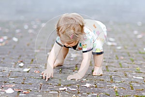 Cute adorable baby girl making first steps outdoors. Healthy happy toddler child learning walking. Lovely girl enjoying