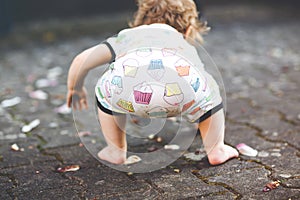 Cute adorable baby girl making first steps outdoors. Healthy happy toddler child learning walking. Lovely girl enjoying