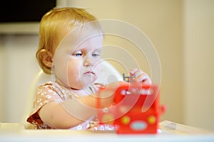 Cute adorable baby girl playing with bright toy at the table. Toddler having fun with eco educational toys. Game and entertainment