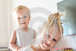 Cute adorable blond caucaian little sister hugging her toddler brother.couple of cheerful sibling playing indoor. Cute girl and