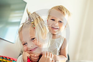 Cute adorable blond caucaian little sister hugging her toddler brother.couple of cheerful sibling playing indoor. Cute girl and