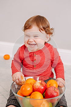 Cute adorable Caucasian baby boy eating citrus fruit. Finny child eating healthy organic snack. Solid finger supplementary food