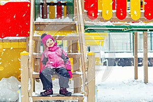 Cute adorable caucasian blond little kid girl having fun enjoy sitting on stairs at children playground covered with