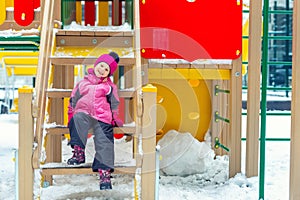 Cute adorable caucasian blond little kid girl having fun enjoy sitting on stairs at children playground covered with