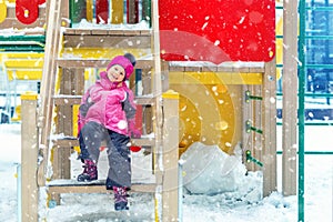 Cute adorable caucasian blond little kid girl having fun enjoy sitting on stairs at children playground covered with