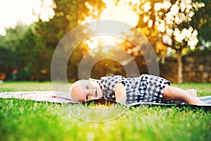 Cute adorable child baby boy lying on the grass on nature