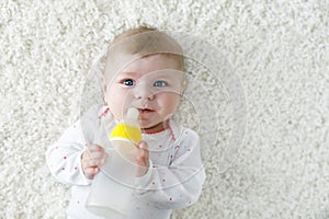 Cute adorable ewborn baby girl holding nursing bottle and drinking formula milk photo