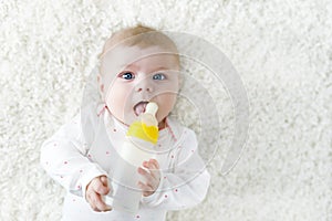 Cute adorable ewborn baby girl holding nursing bottle and drinking formula milk photo