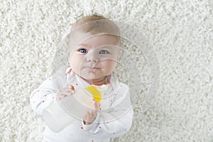 Cute adorable ewborn baby girl holding nursing bottle and drinking formula milk photo