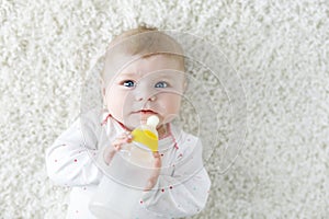 Cute adorable ewborn baby girl holding nursing bottle and drinking formula milk. First food for babies. New born child photo