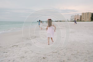 Cute Adorable Happy Young Little Girls in Pretty Dresses Playing On Vacation at the Tropical Beach by the Water on Destination Vac