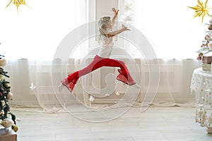 Cute adorable little blond caucasian kid girl fun make dramatic ballet leap contemporary dance in room decor with xmas holiday