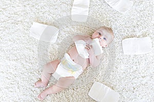 Cute adorable newborn baby of 3 moths with diapers. Hapy tiny little girl or boy looking at the camera. Dry and healthy