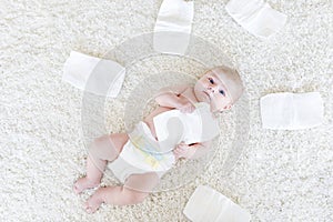 Cute adorable newborn baby of 3 moths with diapers. Hapy tiny little girl or boy looking at the camera. Dry and healthy