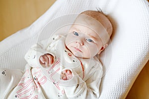 Cute adorable newborn baby againgst white background. New born child, little girl looking surprised at the camera