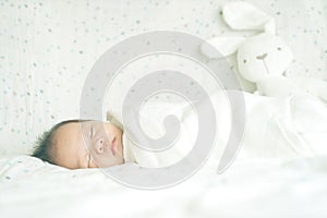 Cute adorable newborn baby boy wrapped or swaddle in a blanket, sleeping in kids bed