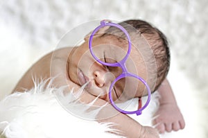 Cute adorable newborn baby with eye glass sleep on furry mat