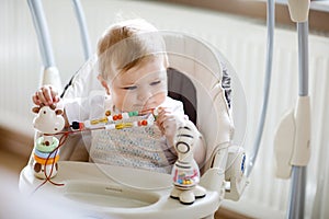 Cute adorable newborn baby girl sitting in swing indoors