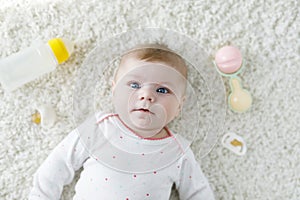 Cute adorable newborn baby playing with colorful pastel rattle toy, nursing milk bottle and dummy. New born child