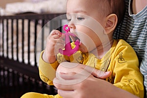 Cute adorable newborn baby playing with colorful rattle toy. baby with teether. six months old lovely baby portrait on