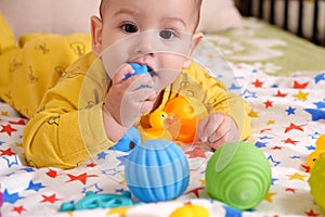 Cute adorable newborn baby playing with colorful rattle toy. baby with teether. six months old lovely baby portrait on