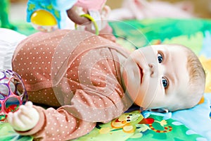 Cute adorable newborn baby playing on colorful toy gym and looking at the camera. Closeup of peaceful child, little baby