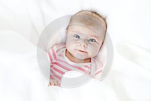 Cute adorable newborn baby in white bed on a blanket. New born child, little adorable girl looking surprised at the