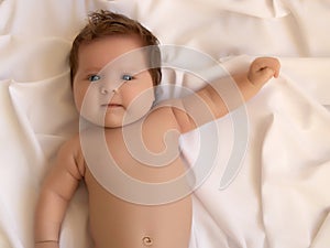 Cute adorable newborn baby in white bed and wrapped in blanket. New born child, little girl looking surprised