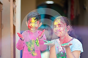 Cute adorable siblings playing with colours during holi festival of colors Indian asian caucasian creative portrait