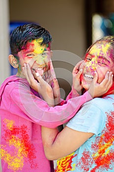 Cute adorable siblings playing with colours during holi festival of colors Indian asian caucasian creative portrait